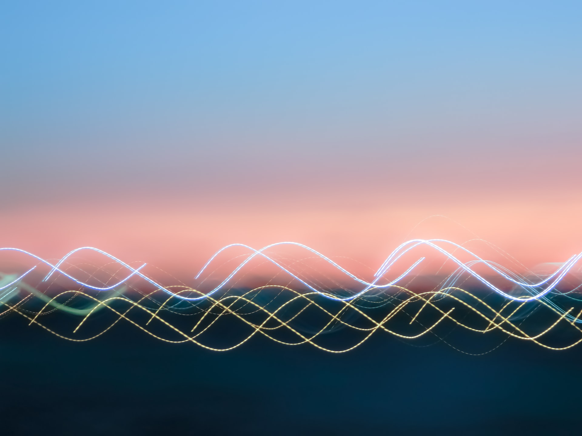 Yellow and white light waves infront of a blurred sunset